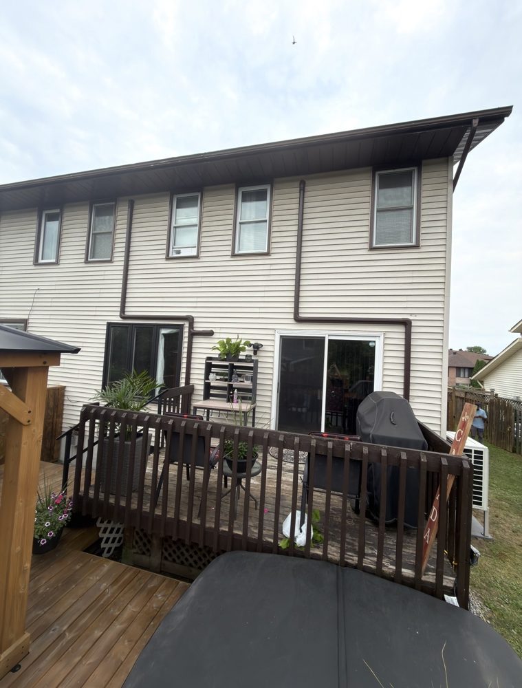Back of a two-storey home with brown heat pump line covers matched to the trim, running to each room